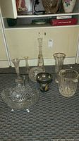 Wide shot showing all the glass and crystal items grouped together on carpet - 5 vases, candy dish, decanter, ice bucket