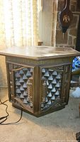 Front and side view of the vintage hexagonal side table showing carved storage panels and wooden legs.