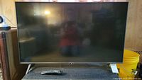 Front view of LG TV on stand with remote control on the stand.