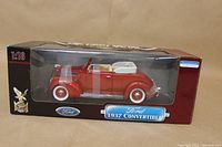 Photo of the 1937 Ford Convertible diecast model in factory sealed box showcasing front and side view with red body and white interior.