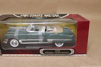 Front view of sealed box containing green 1949 Cadillac Coupe DeVille Convertible model with visible damage to the box.