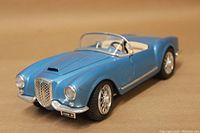 Front and side view showing blue metallic paint, chrome grille, headlights, and windshield with small corner missing.