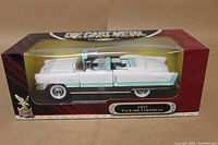 Side view of 1955 Packard Caribbean model car in sealed box showing white and teal convertible design