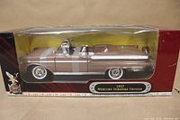 Side view of the 1957 Mercury Turnpike Cruiser model inside factory sealed box showing beige paint and convertible details.