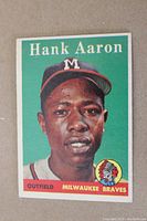 Front of card showing Hank Aaron portrait, green background, yellow name lettering and Braves logo