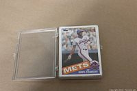 Stack of 1985 Topps New York Mets baseball cards featuring Darryl Strawberry on top, stored in a hard plastic card case.