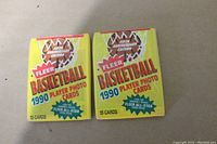 Two unopened wax packs of 1990 Fleer Basketball cards, each containing 15 cards.