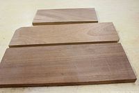 Three mahogany boards arranged on a surface, showing smooth grain and finish from the front side.