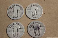 Four heavily worn Standing Liberty quarters showing obverse sides with figure of Liberty holding shield and olive branch.