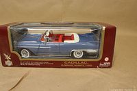 Front view of factory sealed boxed 1/18 scale die cast model showing blue 1958 Cadillac Eldorado Biarritz Convertible with red interior and white convertible top.