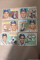 Set of six 1956 Topps Milwaukee Braves baseball cards displayed on surface showing front view of each card with portraits and action shots of players.