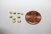 Nine yellow sapphire gemstones shown next to a US penny for size comparison.