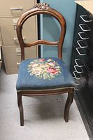Full front view of the mahogany chair showing the needlepoint floral seat and curved backrest.