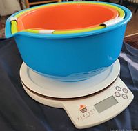 Digital kitchen scale with three nested color-coded mixing bowls on top, showing the product's condition and included accessories.