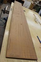 Full length view of a large, flat, quarter-sawn mahogany board on a workshop table showing its width and thickness.