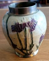 Photo showing small brass vase with purplish-red enamel flower design, green stems, and yellow background with metallic rim top.