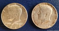 Obverse side of two 1964 Kennedy half dollar coins showing John F. Kennedy's profile and details including date and inscriptions.