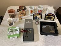 Full lot with all 12 assorted items displayed on table including purse, diecast trucks, mugs, figurines, keychain, trays, and crystal ornaments