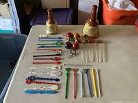 Full view of lot items including 30 swizzle sticks, 4 bar utensils with funny faces, and 2 Wade whiskey bottles arranged on table