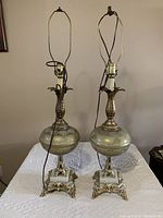 Pair of vintage lamps showing full height with decorative glass midsections and metal bases.
