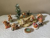 Full set of 10 PenDelfin bunny figurines arranged around the display base with greenery and small dog figurine.