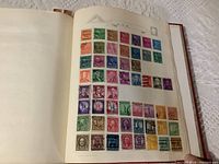 Photo of album page with rows of assorted used USA stamps featuring portraits, historical sites, and symbolic images