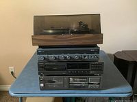Front view of the stack including turntable with dust cover, stereo amplifier, CD player, and cassette player on a table.