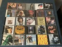 Front view of 25 CD cases arranged in 5 rows of 5, showing album artwork of various artists.