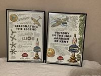 Two framed advertising signs side by side, showing detailed printed text and colorful Spitfire fighter plane illustrations for Spitfire Beer by Shepherd Neame.
