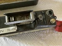 Close-up of one vintage FM radio handie talkie showing on/off and channel selector controls, serial number 2011434, with a large metal handle.