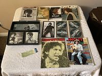 Overview of the entire lot laid out on a white textured cloth showing the CDs, books, magazines, and concert ticket