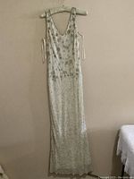 Full view of the vintage beaded gown hanging on a padded hanger, showing the entire length and shape of the gown.