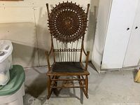 Front view of the vintage wooden rocking chair showing the woven circular backrest with bead accents and solid wooden seat.