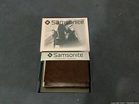 Samsonite wallet closed inside original box showing brand logo on box lid and wallet color and texture.