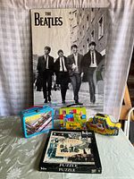 Photo showing entire lot including Beatles poster hung in background, three lunch boxes in front, and puzzle box at bottom.
