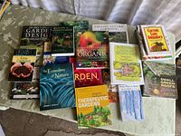Overview of 14 gardening-related books spread on a cloth surface showing titles and colorful covers.