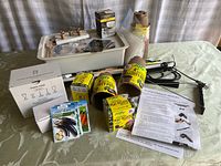 Photo showing hydroponic planting box, seed packets, peat pots, plant grow light box, tubing, air pump, planting tools, and instruction sheets arranged on a table.
