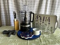 Full view of all items including KitchenAid food processor, knives, Dansk creamer, decorative tray, trivet, hooks, and placemats.
