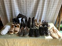 Full lot view showing ten pairs of ladies shoes including sandals, boots, heels, and sneakers in various neutral colors.