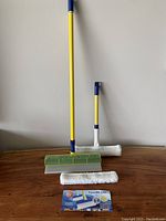 Full view of the extendable Aquablade Squiggy glass cleaner with attached squeegee head and handheld cleaner on a wooden surface.