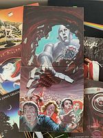 Close-up of Queen News of the World album cover with robot and band members illustration.