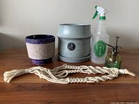 Lot overview showing two ceramic pots (blue/pink and speckled gray), two spritz bottles, and macrame hanger on wooden surface