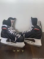 Side view of Hespeler hockey skates with three gold-colored Stanley Cup rings placed in front on the floor.