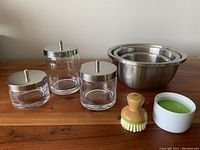 Photo showing the set of three stainless steel mixing bowls nested inside each other and also showing the glass storage jars with stainless steel lids and cleaning brushes.