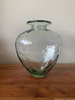 Front view of large green tinted glass vase showing round body and narrow neck with smooth lip.