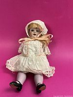 Front full view of doll in original clothing against pink background