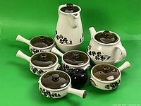 Full set of Denby stoneware including tea pot, coffee pot, and five soup bowls with lids, showing cream color with floral pattern and brown lids.