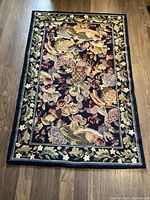 Full view of the rectangular hooked rug laid flat on wood floor