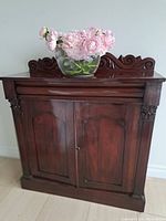 Front view of sideboard with carved scroll crest and closed doors