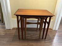 Three teak nesting tables nested together, full view
